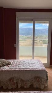 a bedroom with a bed and a large window at Apartamento de lujo mar y montaña para todo el año con calefacción spa gimnasio y piscina climatizada in Tavernes de Valldigna