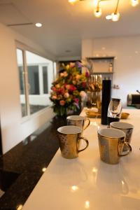 three coffee cups sitting on a counter with flowers at Apartamento Noche Romántica in Bogotá