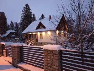 a house with a fence in the snow with lights at Villa Lupus - apartament z prywatną sauną in Szklarska Poręba