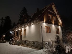 a house with lights on it in the snow at Villa Lupus - apartament z prywatną sauną in Szklarska Poręba +52 photos