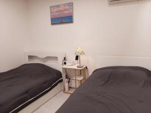 a bedroom with two beds and a table with a lamp at New Hongdae apartment in Seoul