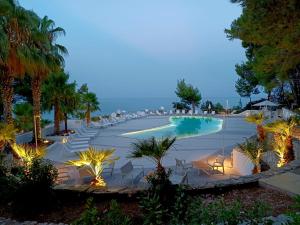 un complexe avec une piscine et des palmiers la nuit dans l'établissement HOTIDAY Hotel Gargano, à Pugnochiuso
