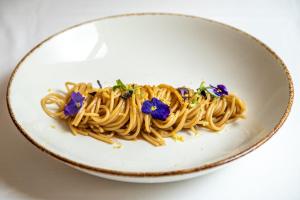 a plate of pasta with purple flowers on it at HOTIDAY Room Collection - Mattinata Faraglioni in Mattinata