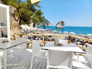 - une plage avec des tables et des chaises blanches et l'océan dans l'établissement HOTIDAY Hotel Gargano, à Pugnochiuso