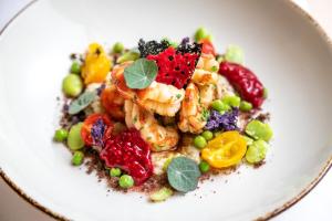 a white plate of food with shrimp and vegetables at HOTIDAY Room Collection - Mattinata Faraglioni in Mattinata