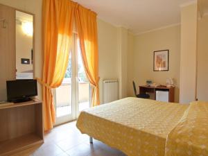um quarto com uma cama, uma televisão e uma janela em Residence Parco del Sole em Rodi Garganico