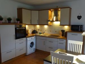 a kitchen with white cabinets and a washer and dryer at BlueteNo1 mit Sauna, Kamin und Garten in Wiesmoor