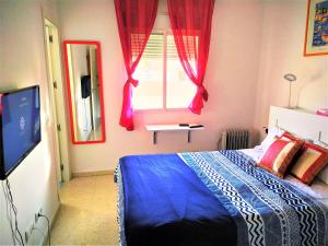 1 dormitorio con cama, ventana y TV en Pino Suite en Sevilla