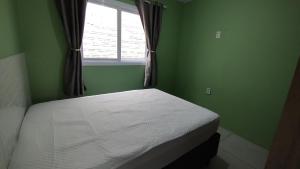 een bed in een groene kamer met een raam bij Casa Mar azul in Torres