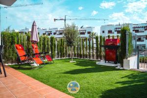 a yard with two chairs and an umbrella and grass at Estrella Del Mar in San Juan de los Terreros