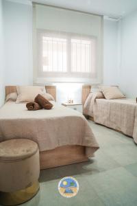 a bedroom with two beds and a chair and a window at Estrella Del Mar in San Juan de los Terreros