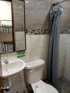 a bathroom with a toilet and a sink and a mirror at Hostal Atlantis in Quito
