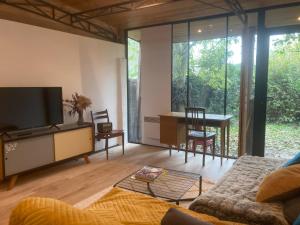 a living room with a couch and a tv and a table at Un jardin en ville in Toulouse