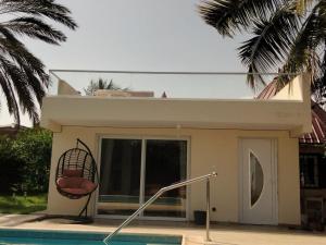 a house with a chair next to a swimming pool at ParadisPlage, 1 minute de la mer in Saly Portudal