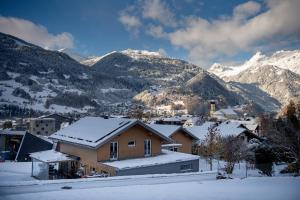 a house in the snow with mountains in the background at Appartments Urmonti in Schruns