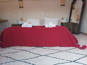 um quarto com uma cama vermelha e toalhas em Zaila Erg Chigaga Luxury Camp em M'hamid