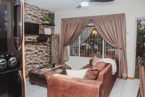 a living room with a leather couch and a window at Villa La'Vie in Witbank