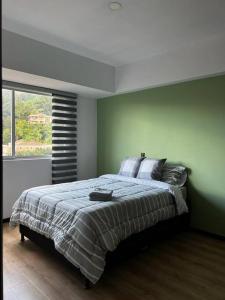 a bedroom with a large bed with a green wall at Sabaneta-Apto familiar in Sabaneta