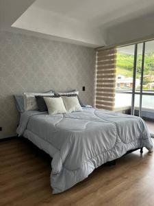 a large bed in a bedroom with a large window at Sabaneta-Apto familiar in Sabaneta