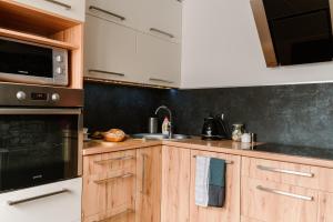 uma cozinha com armários de madeira e uma parede preta em M&M Apartment em Człuchów