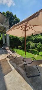 un patio con 2 sillas y una sombrilla grande en Curt da Beta - suggestivo appartamento in Corte del '700, en Malnate