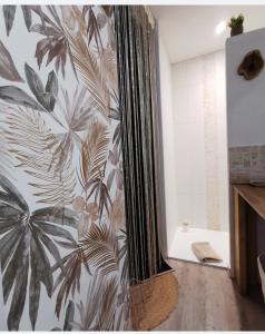 een badkamer met een douchegordijn en een muurschildering van bladeren bij Au Poème du Chêne, Logement indépendant, Intimité, SPA et bien-être in Basse-Goulaine