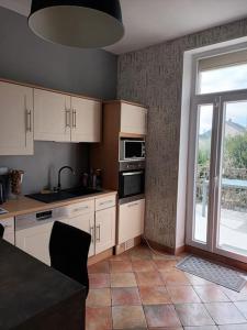 a kitchen with white cabinets and a large window at Villa et visite du vignoble organisée et Piscine in Nuits-Saint-Georges