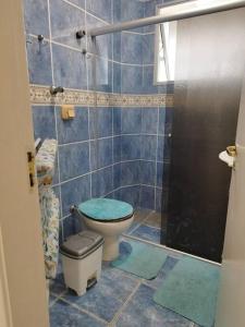 uma casa de banho com um WC e um chuveiro com azulejos azuis em Atravessou a rua tá na praia em São Vicente