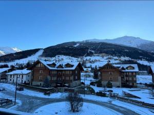 um grupo de edifícios na neve com montanhas em Appartamento incantevole con box e ski room, Wi-Fi, Bormio em Bormio