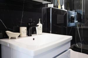 a white bathroom sink with two bottles on it at PARIS Opulent Lifestyle in Drama +27 photos
