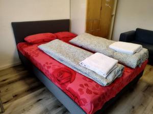 Una cama con sábanas rojas y toallas blancas. en Studio Apartment in City Center, en Sindelfingen 2 fotos más