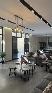 a living room with couches and tables and a kitchen at شالية بيرليز الفندقي in Al Khobar