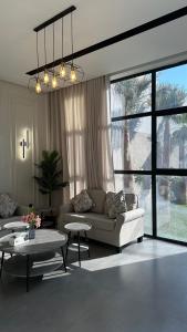 a living room with a couch and tables and windows at شالية بيرليز الفندقي in Al Khobar