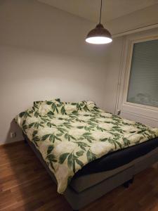 a bedroom with a bed with a green blanket on it at Sauna and the City in Rovaniemi