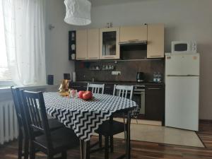 een keuken met een tafel met stoelen en een witte koelkast bij Parkowy Apartment in Bydgoszcz