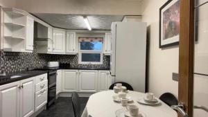 a kitchen with white cabinets and a table with chairs at Spacious home near city hospital in Nottingham