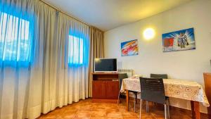 Habitación con mesa con sillas y TV. en Appartamento Smith Roero - Affitti Brevi Italia en Bardonecchia