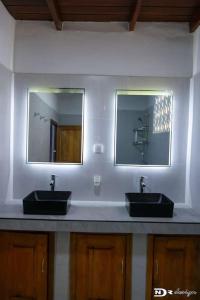 a bathroom with two sinks and two mirrors at Maison « tsarajoro »3ch majunga in Mahajanga