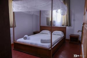1 dormitorio con cama con dosel y sábanas blancas en Maison « tsarajoro »3ch majunga, en Mahajanga