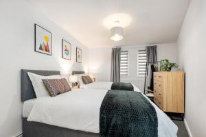 a bedroom with a large white bed and a dresser at ELEGANT suburban APARTMENT in Peterborough