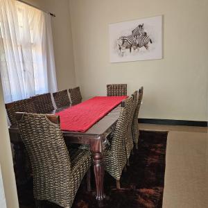a dining room with a table with chairs and a picture of a zebra at Mukamba Private Holiday Home in Livingstone
