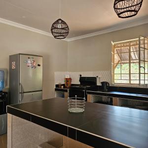 a kitchen with a stainless steel refrigerator and a table at Mukamba Holiday House in Livingstone