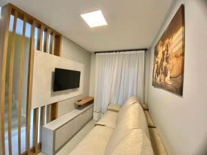 een kamer met een bank, een tv en een raam bij Bellacasa Rua Leão in Bombinhas