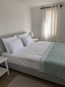 um quarto com uma cama grande com lençóis brancos e almofadas em Apartment Ana em Otok