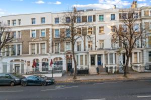 twee auto's geparkeerd voor een groot gebouw bij Notting Hill: Stylish 1BR with Terrace - Suite Inn in Londen