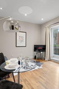 een eetkamer met een glazen tafel en een televisie bij Notting Hill: Stylish 1BR with Terrace - Suite Inn in Londen