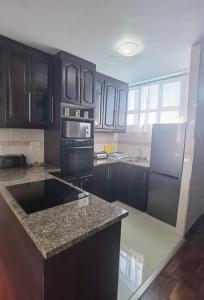 a kitchen with black cabinets and a black refrigerator at Lela Holiday Apartments in Durban