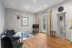 een woonkamer met een tafel en een televisie bij Notting Hill: Stylish 1BR with Terrace - Suite Inn in Londen