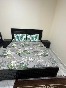 1 dormitorio con 1 cama con colcha de flores en لولي قست هاوس, en Al Ain