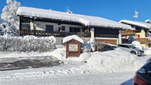 ein schneebedecktes Haus mit einem Haus in der Unterkunft Gästehaus Gaisalpe in Fischen im Allgäu